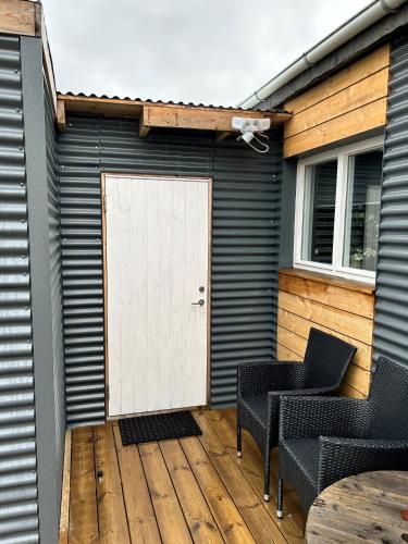 a patio with two chairs and a white door at The Little Guesthouse Downtown - Keflavik Airport in Keflavík