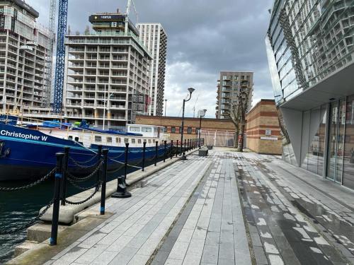 a dock with a blue boat in a city at Canary Wharf Holiday Rooms in London
