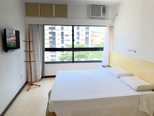 a bed in a room with a large window at Ondina Apart Hotel Residences in Salvador