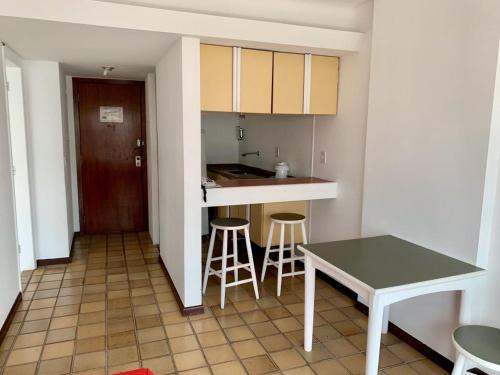 a small kitchen with a table and stools in it at Ondina Apart Hotel Residences in Salvador