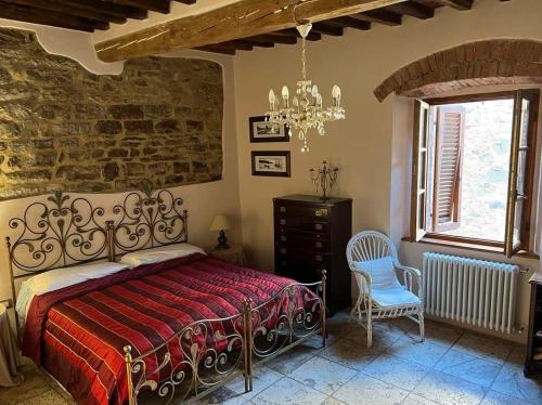een slaapkamer met een bed, een stoel en een raam bij La Piazzetta Toscana B&B in Campiglia Marittima