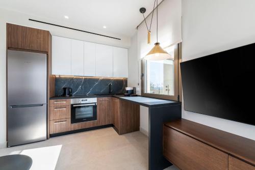 a kitchen with wooden cabinets and a large screen tv at Maravilla Luxury Living in Kos Town