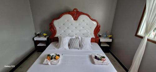 a bedroom with a white bed with a large headboard at Frankfurt Cottages in Mbale