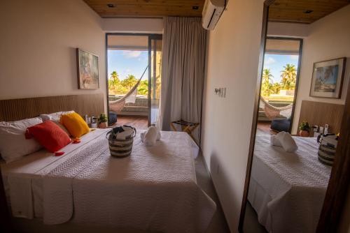 1 dormitorio con 2 camas y espejo en Milagres Hospedagens - Cobertura Rota 206 - Capela & Praia, en São Miguel dos Milagres