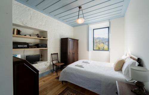 a bedroom with a bed and a tv and a window at Casas de Vila Pouca in Mondim de Basto