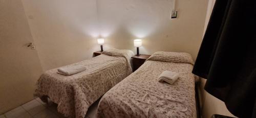 2 camas en una habitación pequeña con 2 lámparas. en Deptos Dean Funes 45 CENTRO en Salta