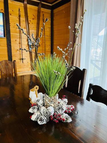 a wooden table with a vase of grass and flowers at Котедж Chalet Adriana in Bukovel