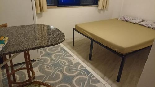 um pequeno quarto com uma mesa e uma mesa e um banco em Apartamento da sereia itapua em Salvador