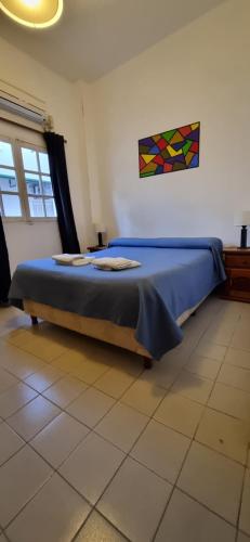1 dormitorio con 1 cama con sábanas azules y una pintura en la pared en Deptos Dean Funes 45 CENTRO en Salta