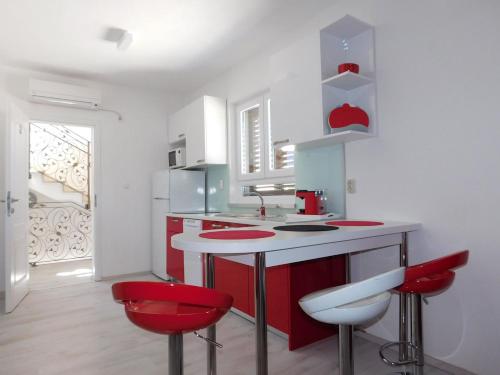a kitchen with red and white counters and red stools at Apartments with parking space Povlja, Brac - 21089 in Povlja