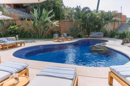 a swimming pool with lounge chairs and a swimming pool at La Villa Luz (sólo adultos) in Zihuatanejo
