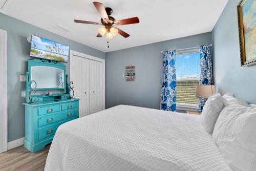 a blue bedroom with a bed and a ceiling fan at Walk to Beach, Secluded, Gazebo with Grill, 1GiG WiFi, Washer and Dryer, Games in Gulf Shores