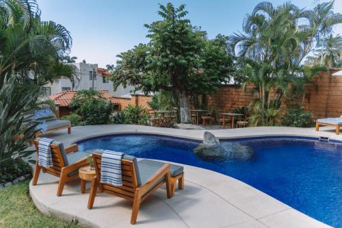 a swimming pool with two chairs and a turtle fountain at La Villa Luz (sólo adultos) in Zihuatanejo