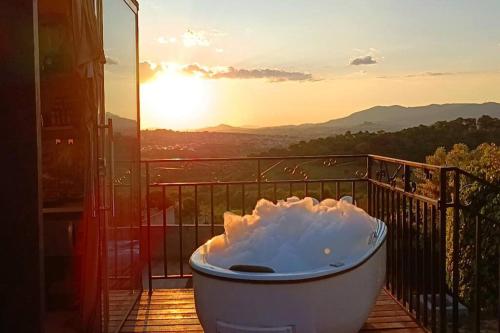 a bath tub sitting on a balcony with the sunset at Tiny House Paraiso Minicasas Com Hidromassagem in Pouso Alegre