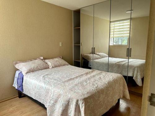1 dormitorio con 2 camas y espejo en Departamento en Ñaña, Chaclacayo, Lurigancho - Chosica, en Alto Peru