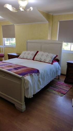 Un dormitorio con una cama blanca con almohadas. en Habitación 1 casa/tinaja/piscina, en Valdivia