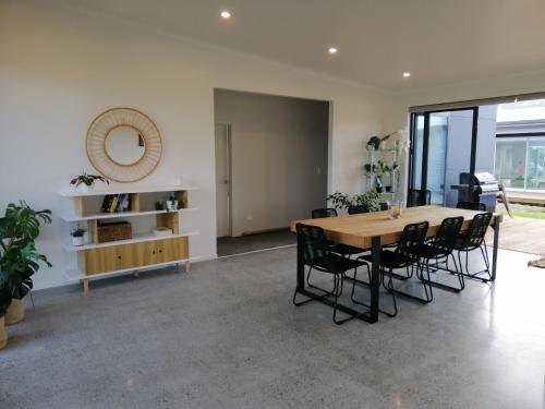 a dining room with a table and chairs and a mirror at Purangi Beachhouse in Cooks Beach