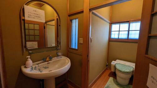 a bathroom with a sink and a mirror and a toilet at 富士吉田かつまたや in Fujiyoshida