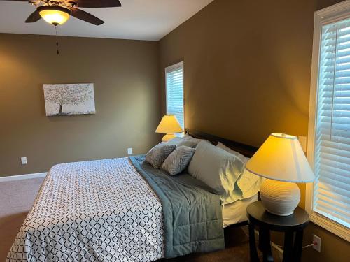 a bedroom with a bed with two lamps and two windows at Five Stars Luxury Home in Clarksville