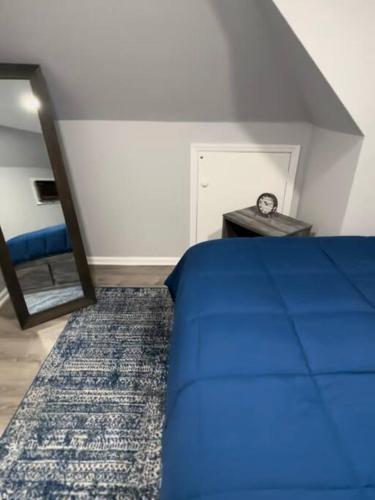 a bedroom with a blue bed and a clock on a table at Cozy Studio with 1 Bed & Comfy Sofa Bed in New Rochelle