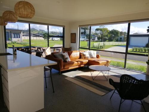 a living room with a couch and a table at Purangi Beachhouse in Cooks Beach