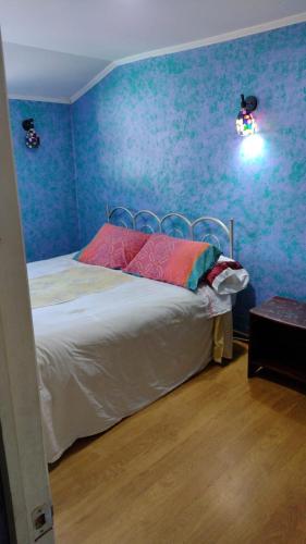 een slaapkamer met blauwe muren en een bed met roze kussens bij HABITACION 2 CON BAÑO PRIVADO in Valdivia