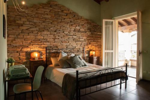 - une chambre dotée d'un mur en briques avec un lit et des chaises dans l'établissement Terra Sole Aria Home Brescia, à Piazza