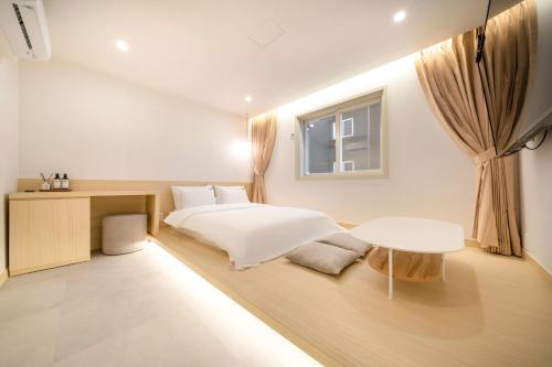 a bedroom with a bed and a table and a window at Nomad Aank Hotel Gumi in Gumi