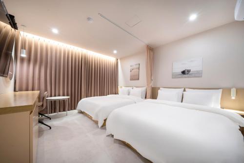 a hotel room with two beds and a television at Nomad Aank Hotel Gumi in Gumi