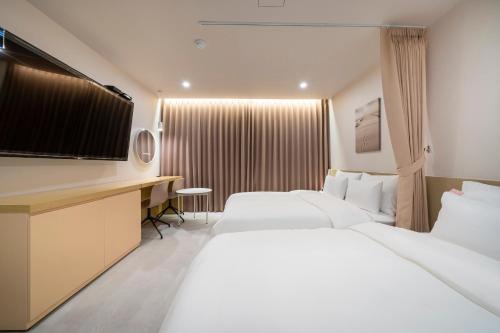 a hotel room with two beds and a flat screen tv at The Hyoosik Nomad Aank Hotel Gumi in Gumi