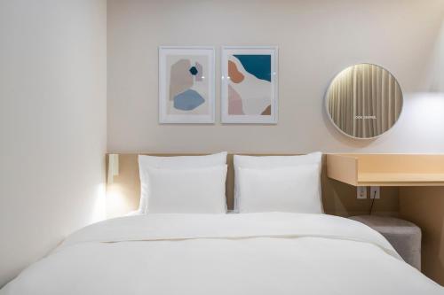 a bedroom with a white bed and a mirror at Nomad Aank Hotel Gumi in Gumi