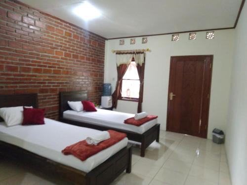 una camera con due letti e un muro di mattoni di Penginapan Homestay Mudiyono Syari'ah a Borobudur