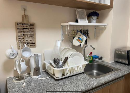 a kitchen counter with dishes in a strainer next to a sink at Marikina Manila Condominium 1 Bedroom in Manila