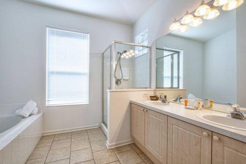 a bathroom with a sink and a tub and a mirror at Pool Home in Famous Windsor Palms Resort 4 Miles to Disney, Free Resort Amenities in Kissimmee