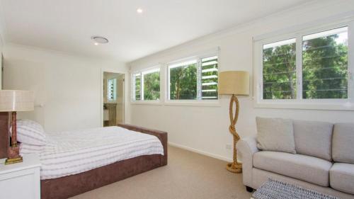 a bedroom with a bed and a couch and windows at Beachworth - Wifi & Pet Friendly in Pearl Beach