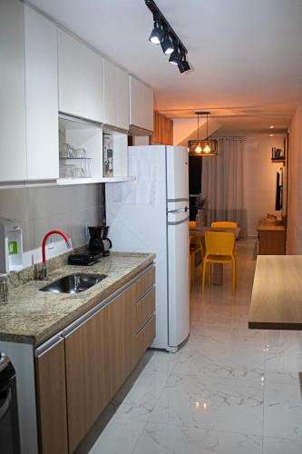 a kitchen with a sink and a white refrigerator at Luxo com Spa exclusivo no paraíso do Peró! in Cabo Frio