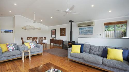 a living room with two couches and a table at Pippi Rikki - Pearl Beach With Wifi in Pearl Beach