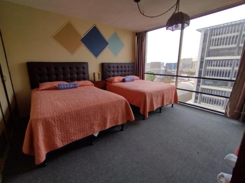 ein Hotelzimmer mit 2 Betten und einem großen Fenster in der Unterkunft Apartamento 1007 Cortijo Reforma zona 9 in Guatemala