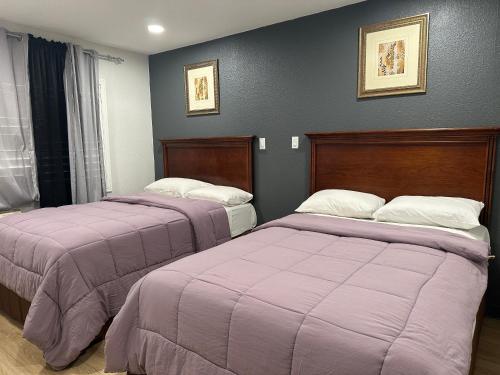 2 bedden in een kamer met paarse dekens bij Bartlett Motel in Lomita