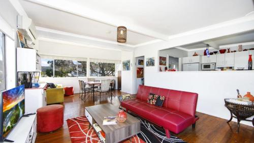 - un salon avec un canapé rouge et une table dans l'établissement Patonga Corner Creek - Water Glimpses, à Patonga Beach