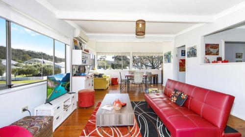a living room with a red couch and a table at Patonga Corner Creek - Water Glimpses in Patonga
