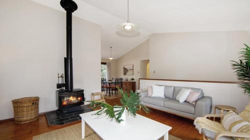 a living room with a couch and a wood stove at Hidden Treasure - Family Friendly Holiday Home in Pearl Beach