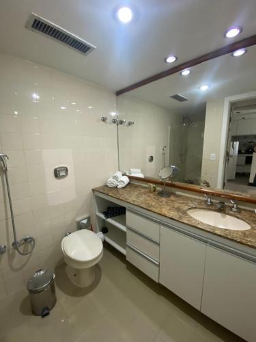 a bathroom with a toilet and two sinks and a mirror at Ondina Apart Hotel Residences in Salvador
