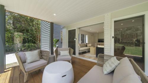 a living room with a couch and chairs on a porch at Hop Skip and Jump To The Beach in Pearl Beach