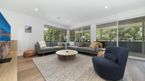 a living room with two couches and a table at Hop Skip and Jump To The Beach in Pearl Beach