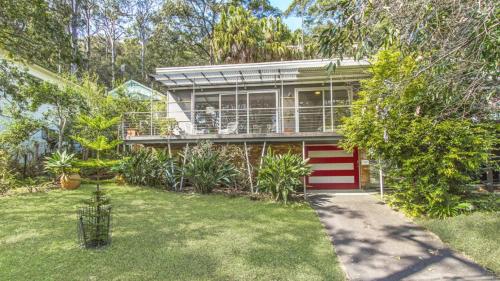 a house with a red garage in a yard at Hillside Hideaway - Wifi & Pet Friendly in Pearl Beach