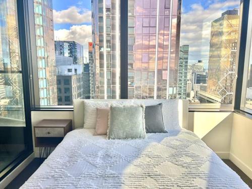 a bed in a room with a large window at Stunning 2-Bed Apartment with Panoramic CBD Views in Melbourne