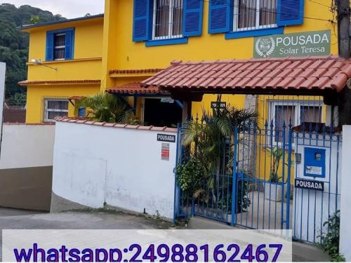 een geel en blauw gebouw met een poort bij Pousada Solar Teresa in Petrópolis