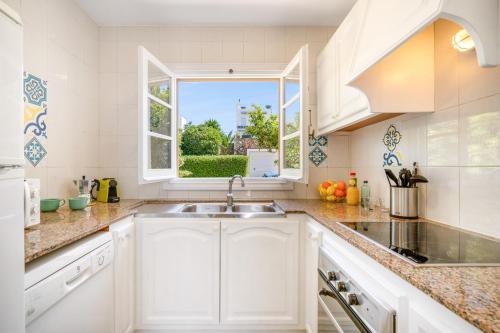 a white kitchen with a sink and a window at Can Poriol in Alaior