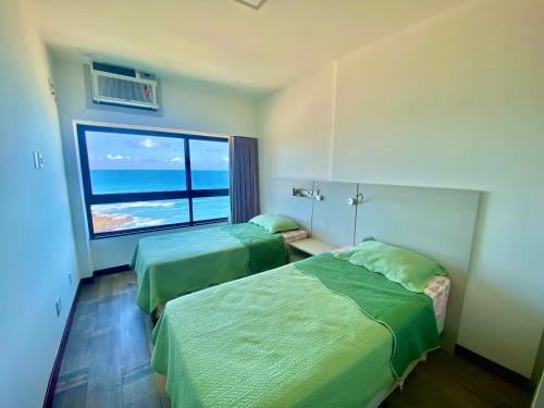 a hotel room with two beds and a large window at Ondina Apart Hotel Residences in Salvador